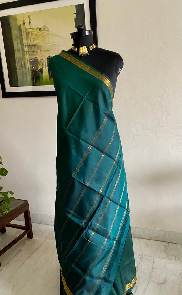 SOUNDARYA- THE REGAL CHARM OF BOTTLE GREEN SILK WITH INTRICATE ZARI WORK ALONG THE BORDER