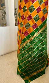 TVESHA- ORANGE GHARCHOLA WITH BANDHANI CHOWK AND GREEN BORDER