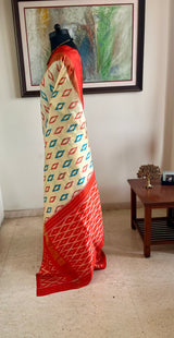 AVINI – VIBRANT RAJKOT PATOLA IN CREAM AND ORANGE