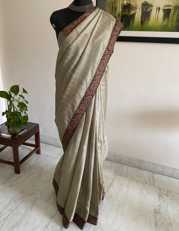 PAAVANI- AN UNUSAL KHAKI BEIGE TUSSAR WITH AN EMBROIDERED BORDER RUNNING THROUGH THE LENGTH OF THE SAREE.