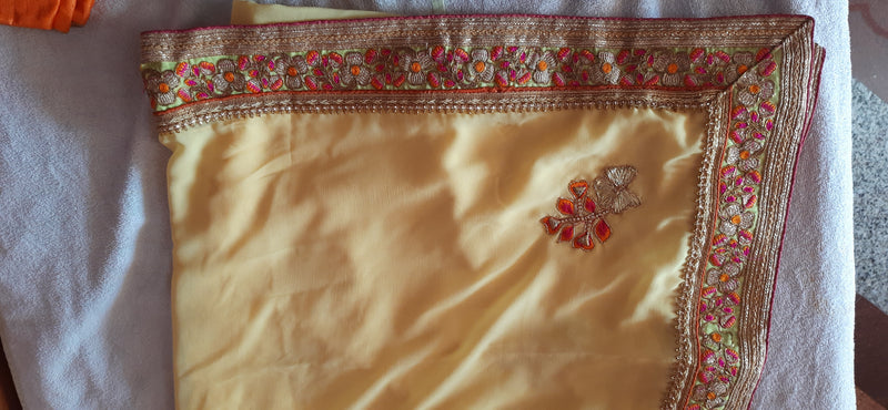 GAURI- A SOFT YELLOW GEORGETTE SAREE WITH BEAUTIFUL RUST AND GOLD EMBROIDERED BORDER AND SCATTERED FLORAL EMBROIDERY IN THE BODY, INCLUDES STITCHED BLOUSE