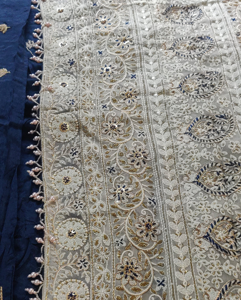 SHARMILA- AN EXQUISITE PURE SILK CHIFFON IN GREY WITH ELABORATE CHIKANKARI INSPIRED MACHINE EMBROIDERY AND HAND ZARDOSI WORK IN THE UPPER PART OF THE SAREE.  A CONTRAST BORDER OF MIDNIGHT BLUE IN SATIN SILK, EMBROIDERED SILK CONTRAST BLOUSE PIECE