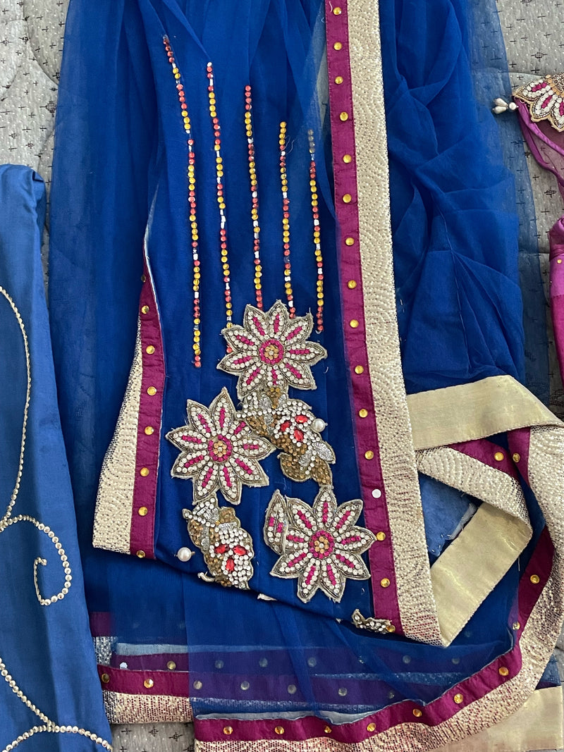 NAVYA NAVELI- A BEAUTIFUL NET SAREE IN BLUE WITH GOLDEN AND PINK BORDER BROOCH STYLE FLORAL WORK ON THE SHOULDER. COMES WITH A SATIN PETTICOAT WITH SEQUIN WORK ON IT AND A CONTRAST PINK AND MAROON STITCHED BLOUSE